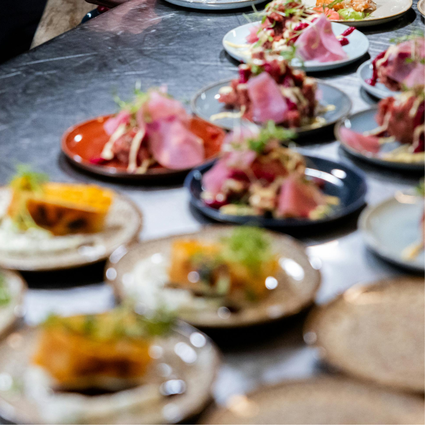 Small plates of canapés laid out across a wide dark counter for a private event.