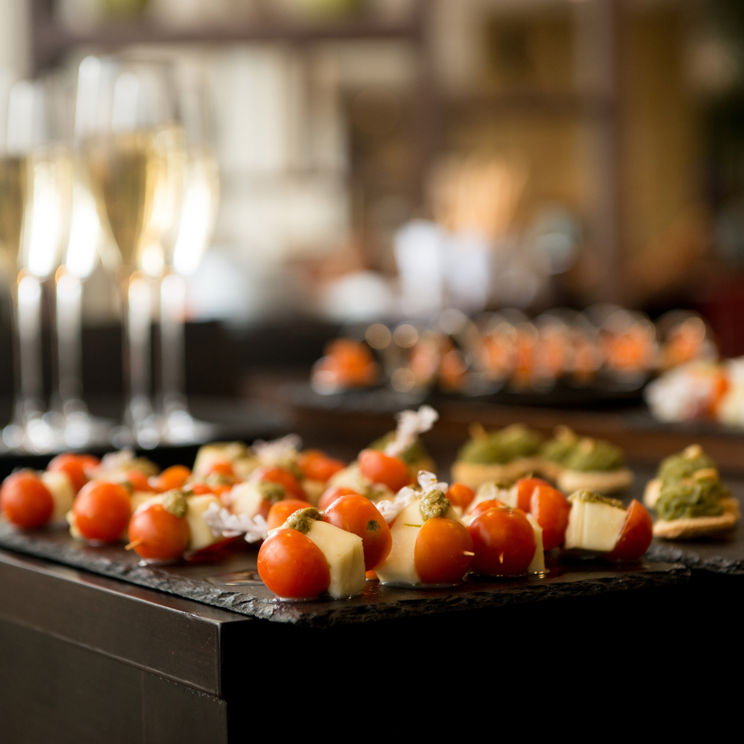 Small canapés and champagne flutes lit warmly at a private event.
